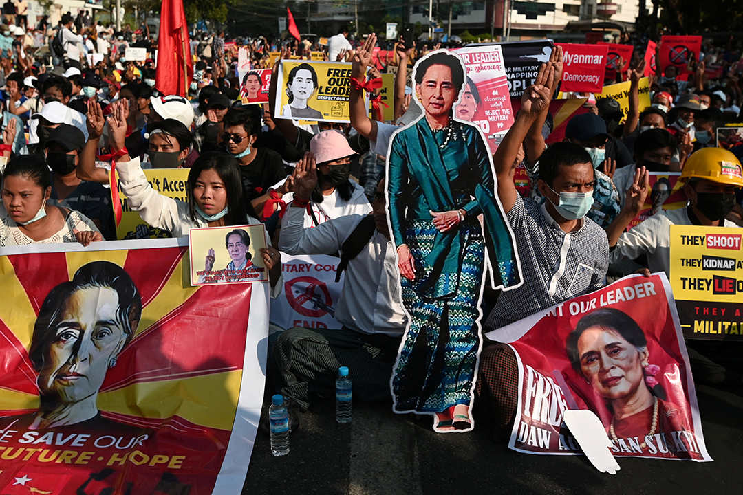 Demonstrators hold placards with the image of Aung San Suu Kyi