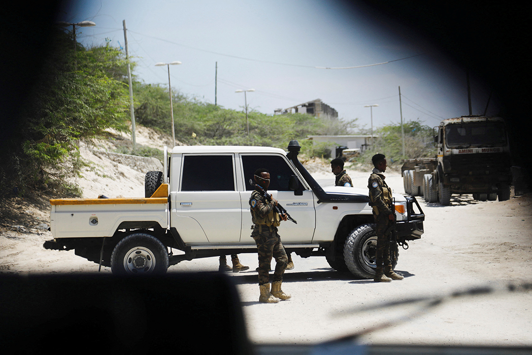 Soldier stand around a white pickup truck.