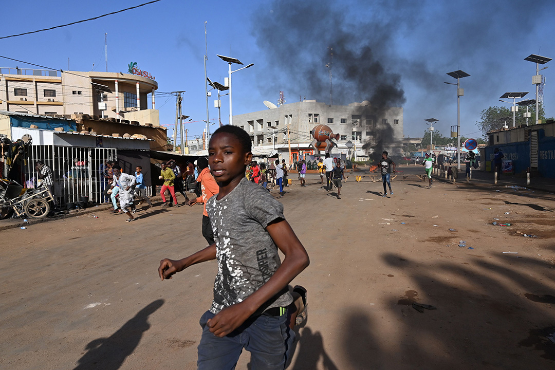 A boy runs away from billowing smoke in a town center.