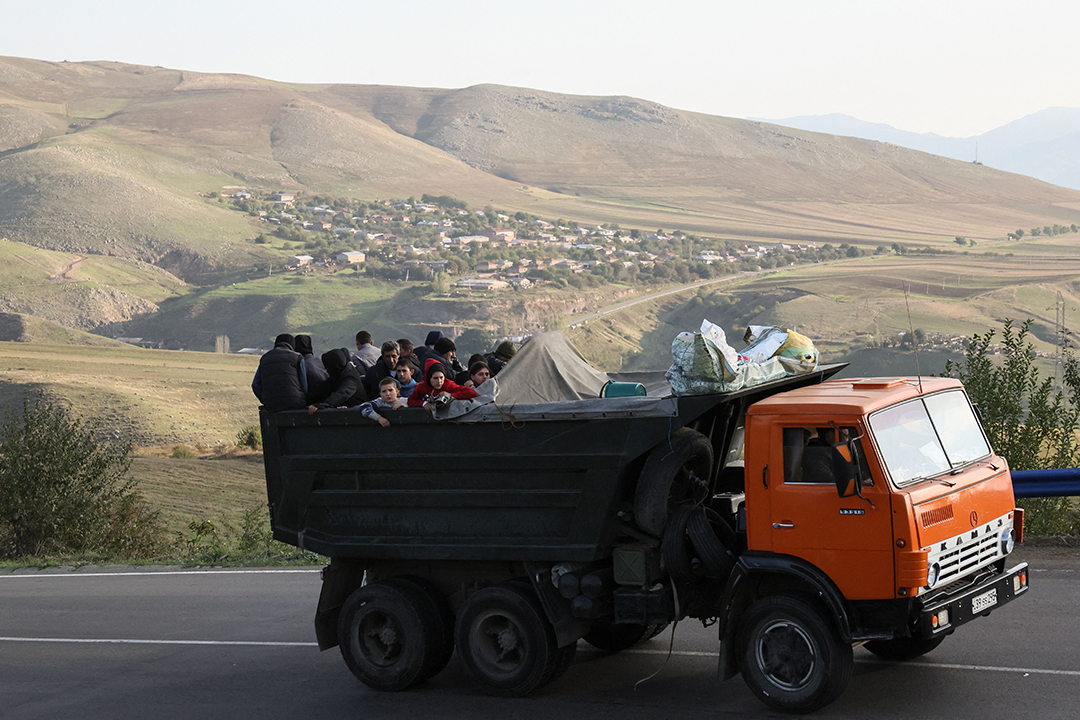 A truck holding a group of people drives through mountains.