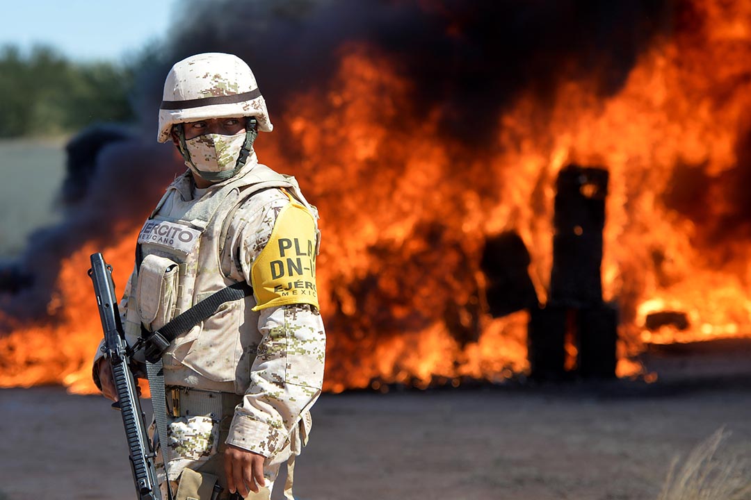 A man stands in front of an orange blazing fire